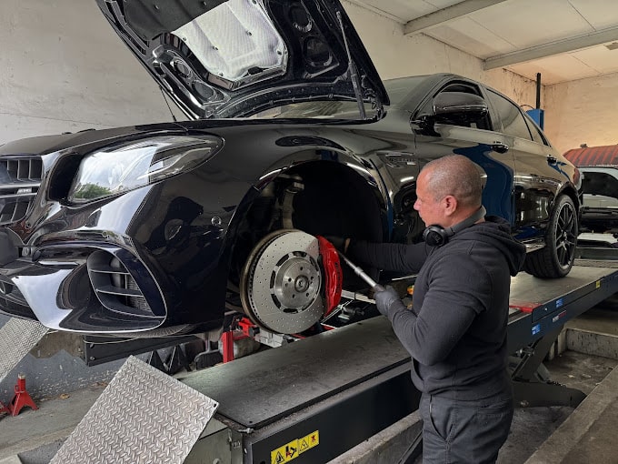 A technician tending to the brake discs on a black car. 