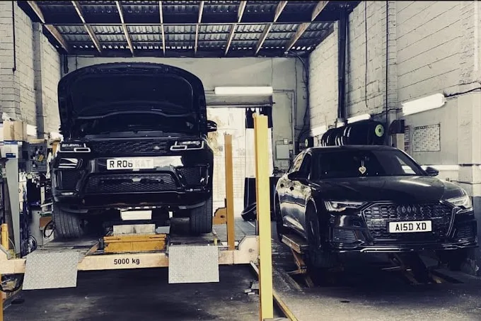 A black Audi and a black Range Rover on ramps side by side. 