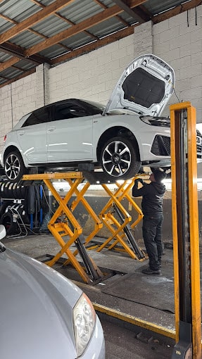 A white car on a ramp with a technician working underneath.